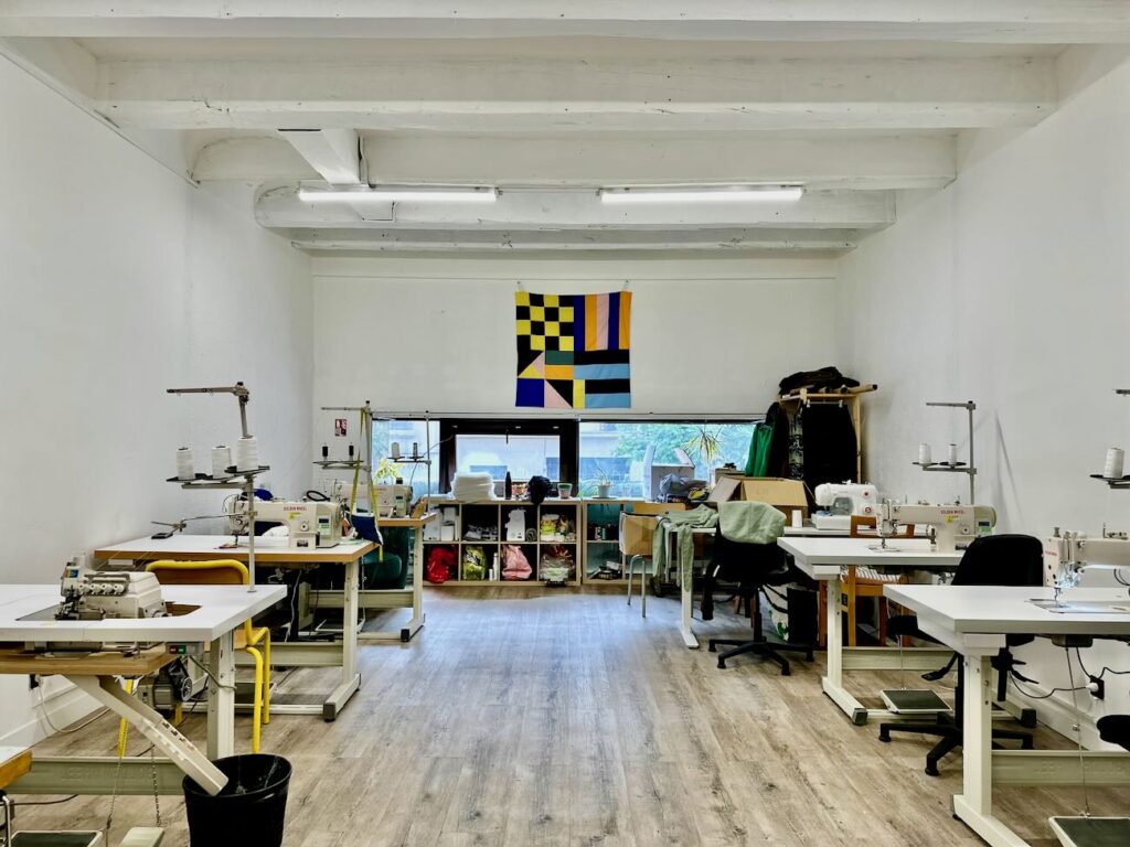 Atelier Regain est une atelier de création de mode durable qui propose sous sa marque éponymes des vêtements upcyclés issus de dons et conçus par des publics en insertion. (salle de couture)