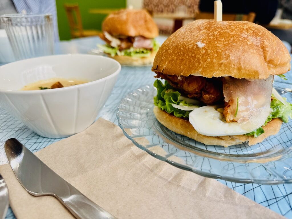 Club César est une cantine de quartier où il est possible de s’attabler pour un café, un déjeuner et un goûter. L’adresse dispose également d’une offre épicerie. (burger poulet)